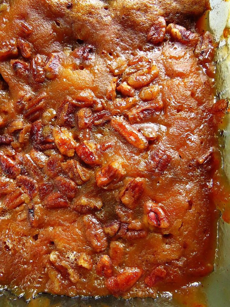 a close up of food in a pan with sauce on the bottom and pecans around it