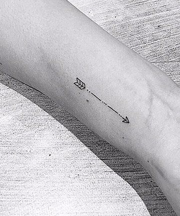 a black and white photo of a person's arm with an arrow tattoo on it