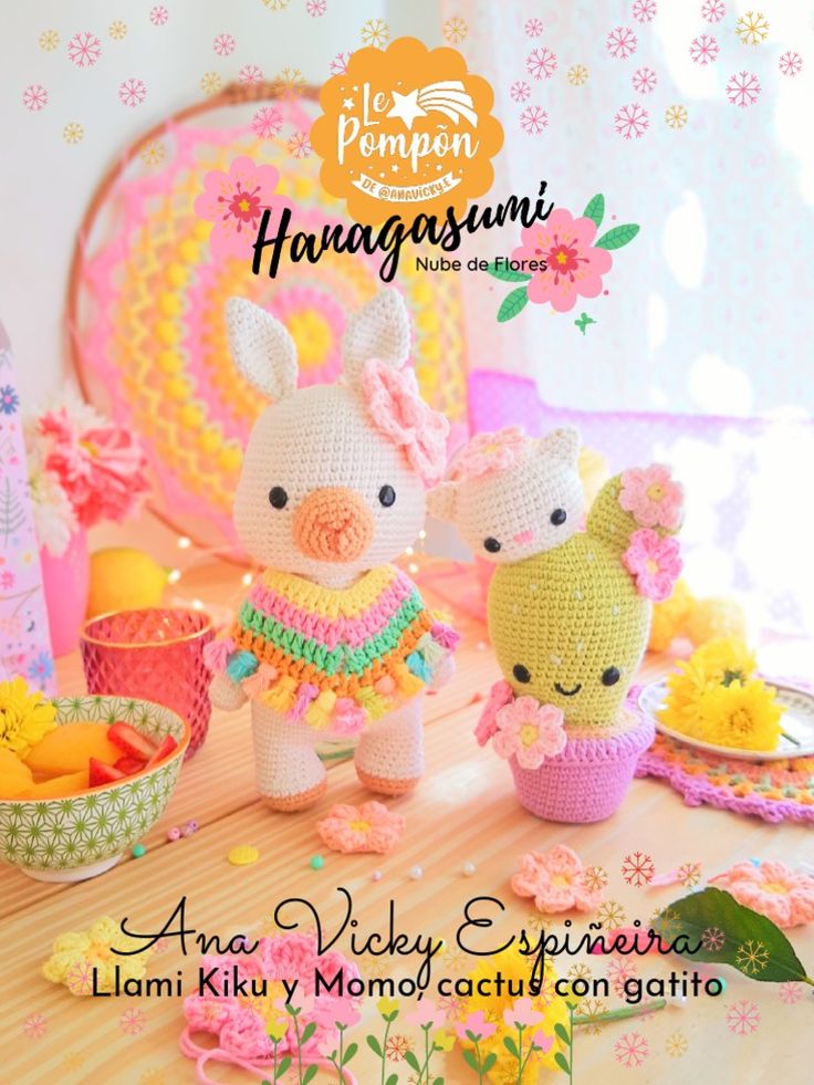 two crocheted animals standing next to each other on a table with plates and flowers