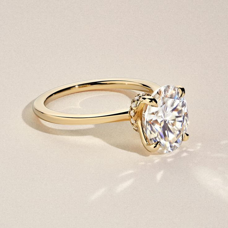 a yellow gold engagement ring with a round cut diamond in the center, on a white background