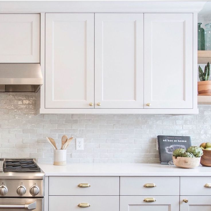 a kitchen with white cabinets and stainless steel stove top oven in the center, surrounded by wooden utensils