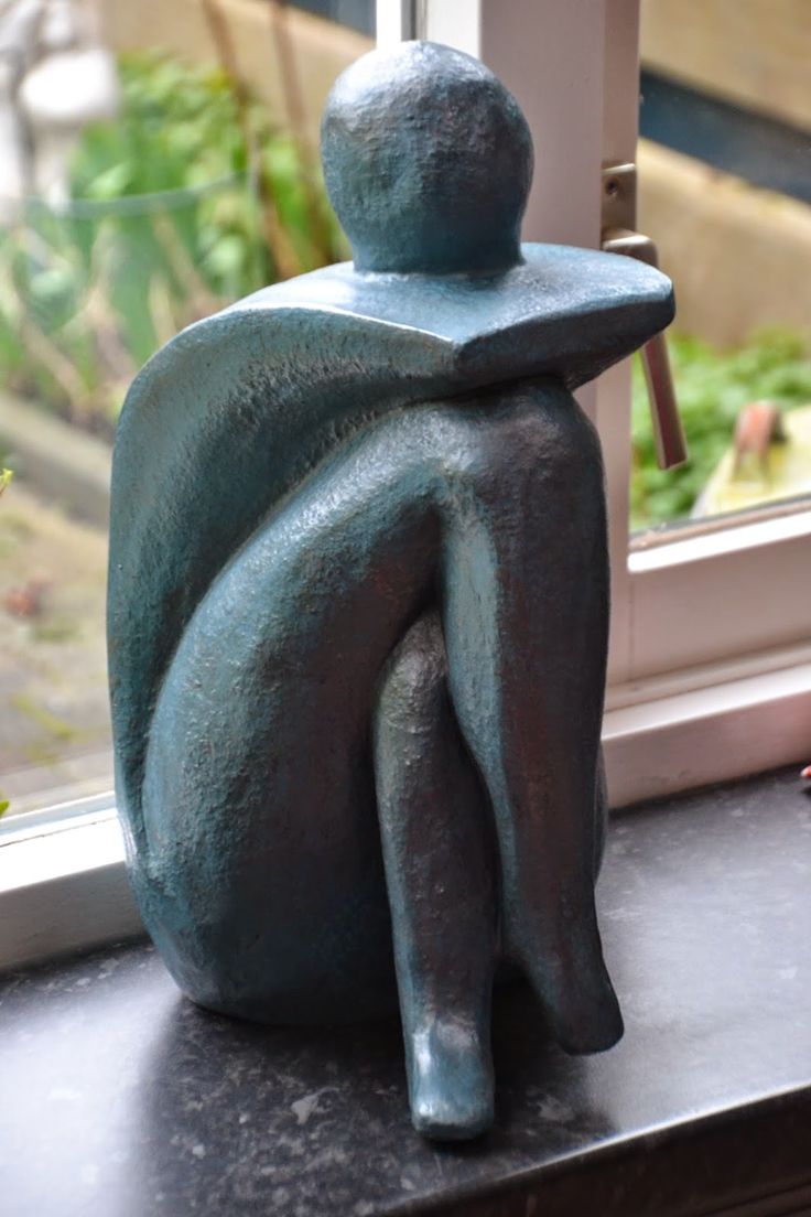 a small statue sitting on top of a window sill next to a planter