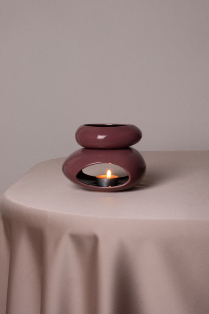 a lit candle sitting on top of a table next to a white cloth covered table