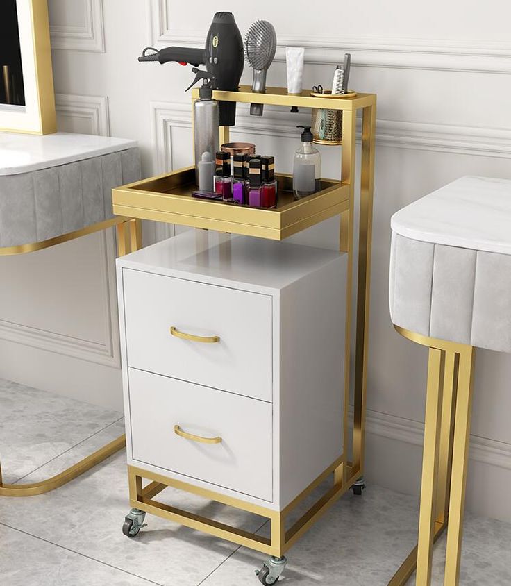 two white and gold tables with drawers in a room