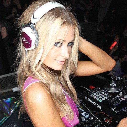 a woman with headphones is playing music on a dj's turntable at a party