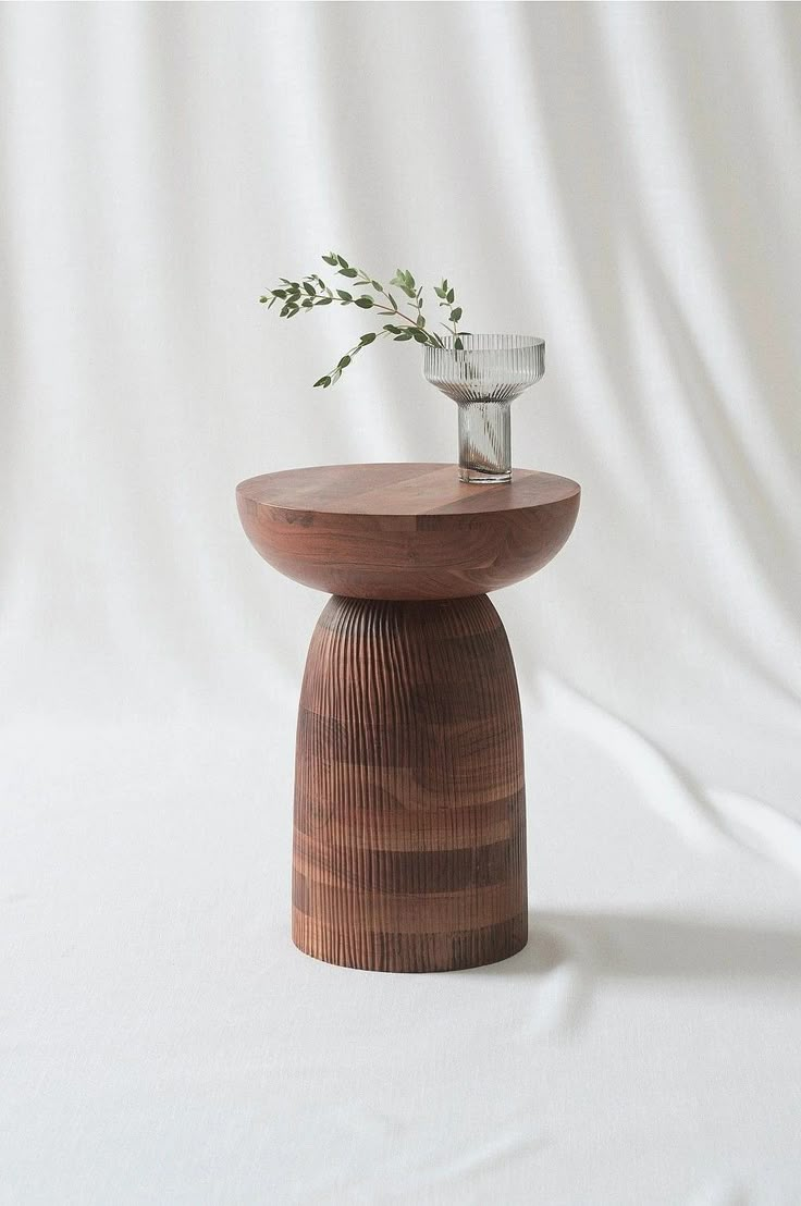 a wooden table with a glass vase on top and a plant growing out of it