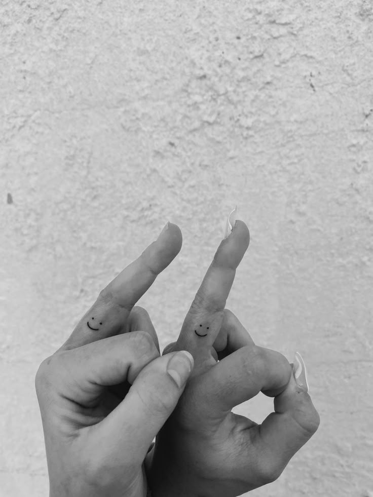 two hands making the peace sign with their fingers, one holding an object in the other's hand