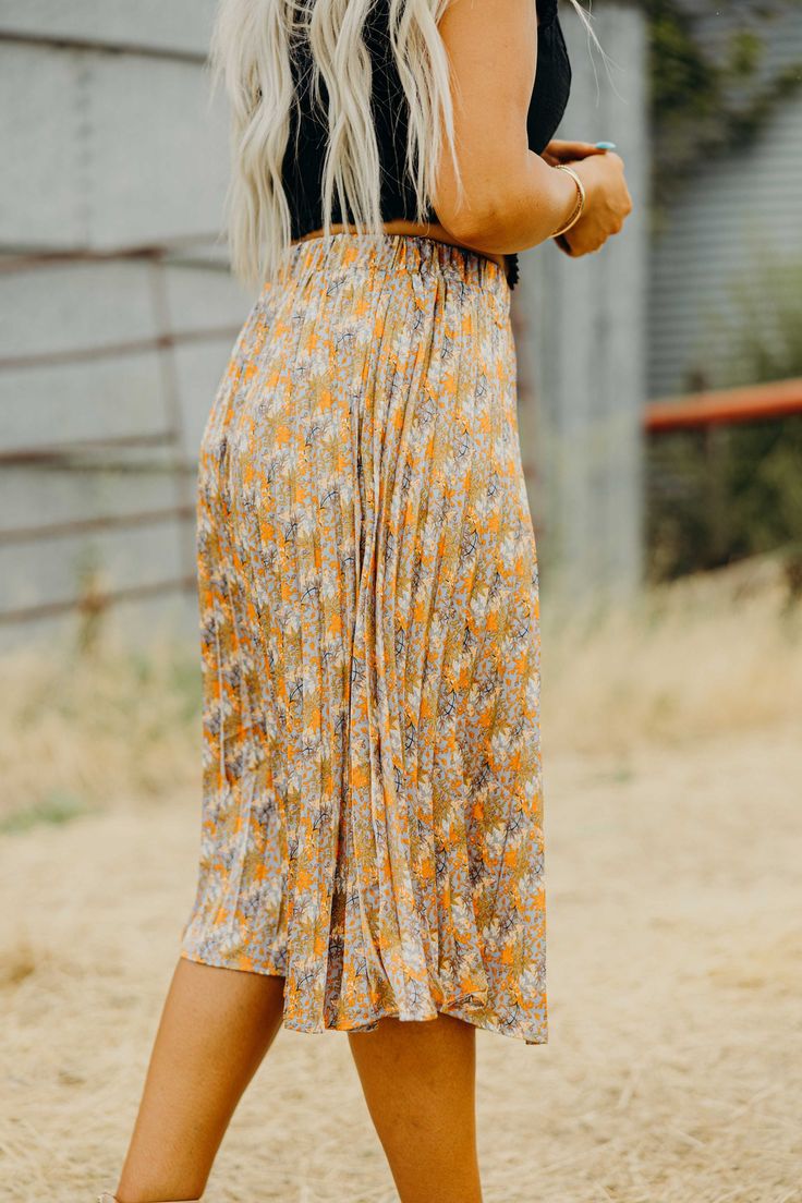 Introducing the must-have Cascade Skirt! This stunning midi length skirt features a beautiful floral print, creating a romantic and feminine look. The pleated design adds texture and movement to your outfit, while the banded waist keeps you comfortable all day long. Perfect for fall, this western skirt is a versatile addition to your wardrobe. Kiah is wearing size medium paired with The Diann Corset and The Dunstan Vest Spring Flowy Skirt With Elastic Waistband, Flowy Lined Pleated Skirt For Spring, Flowy Long Pleated Skirt For Day Out, Spring Pleated Maxi Skirt, Feminine Spring Pleated Maxi Skirt, Floral Print Flowy Skirt, Spring Flowy Skirt With Pleated Hem, Spring Midi Length Gathered Skirt, Spring Midi Pleated Skirt With Elastic Waistband