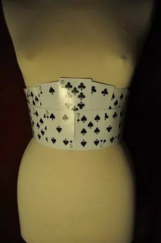 a mannequin wearing a white and black belt with playing cards on it