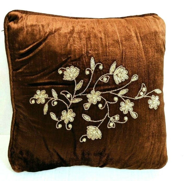 a brown pillow with white embroidered flowers on it