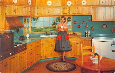 a woman standing in the middle of a kitchen next to a table and stove top oven