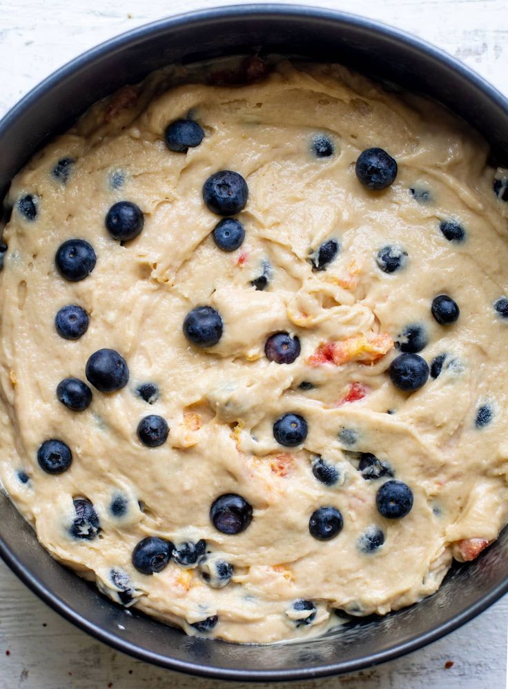 a pan filled with batter and blueberries on top of a table