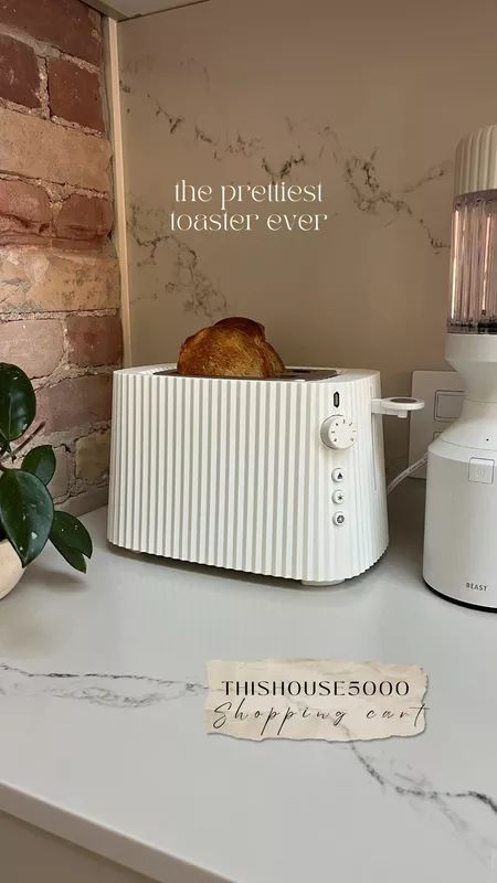 a toaster sitting on top of a white counter next to a potted plant