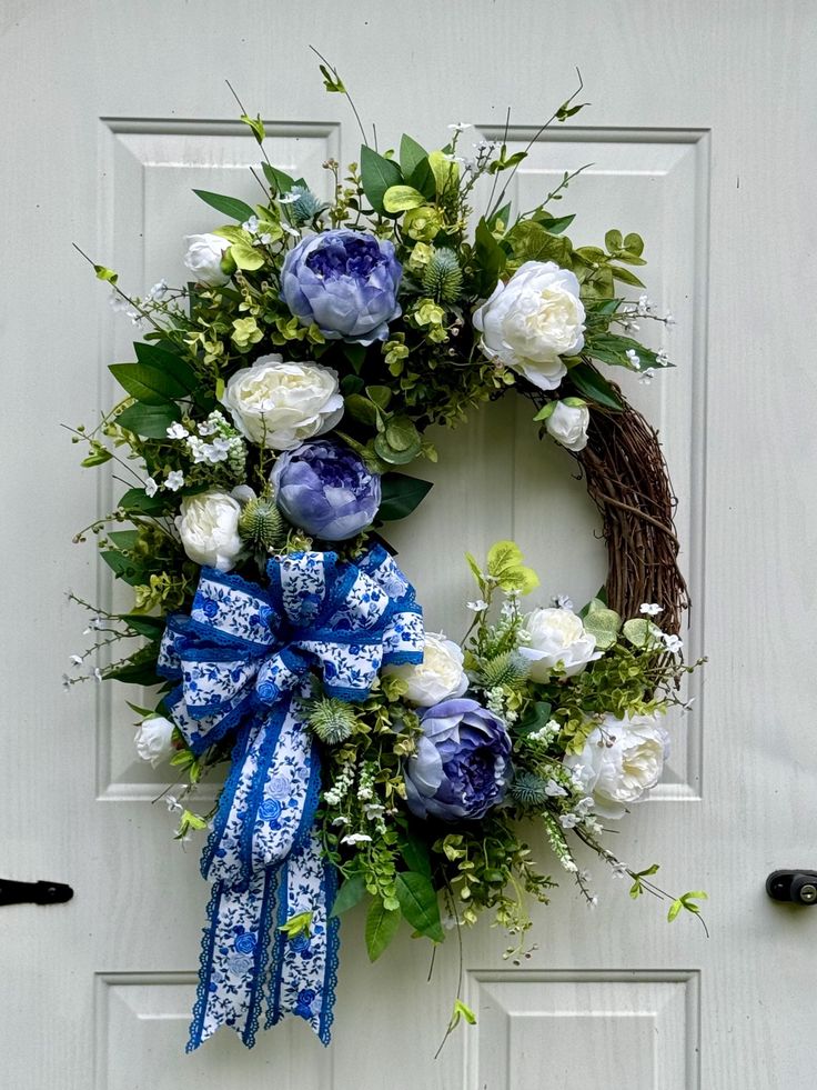 a wreath with blue and white flowers hanging on a door