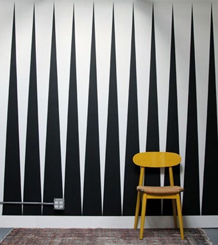 a yellow chair sitting in front of a black and white wall