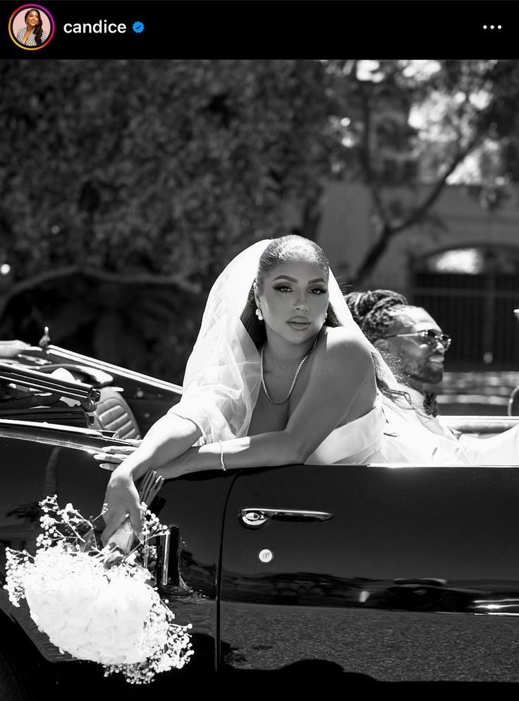 black and white photograph of a bride in the back of a convertible car with her groom