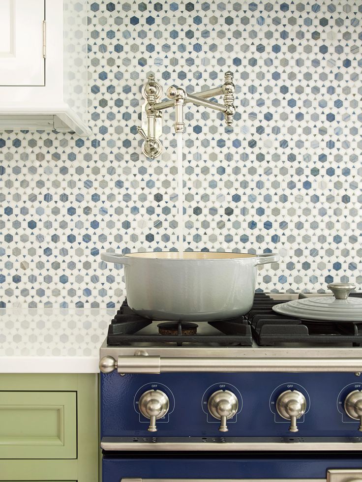 a stove top oven sitting next to a wall with blue and white flowers on it