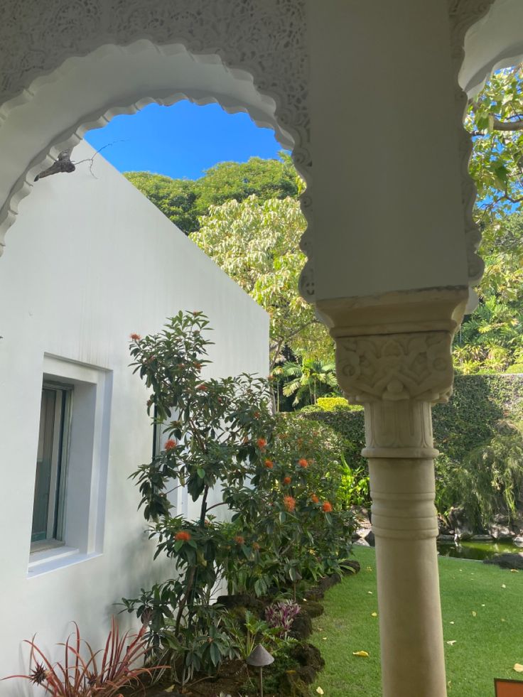 an archway leading to a white building with trees in the background