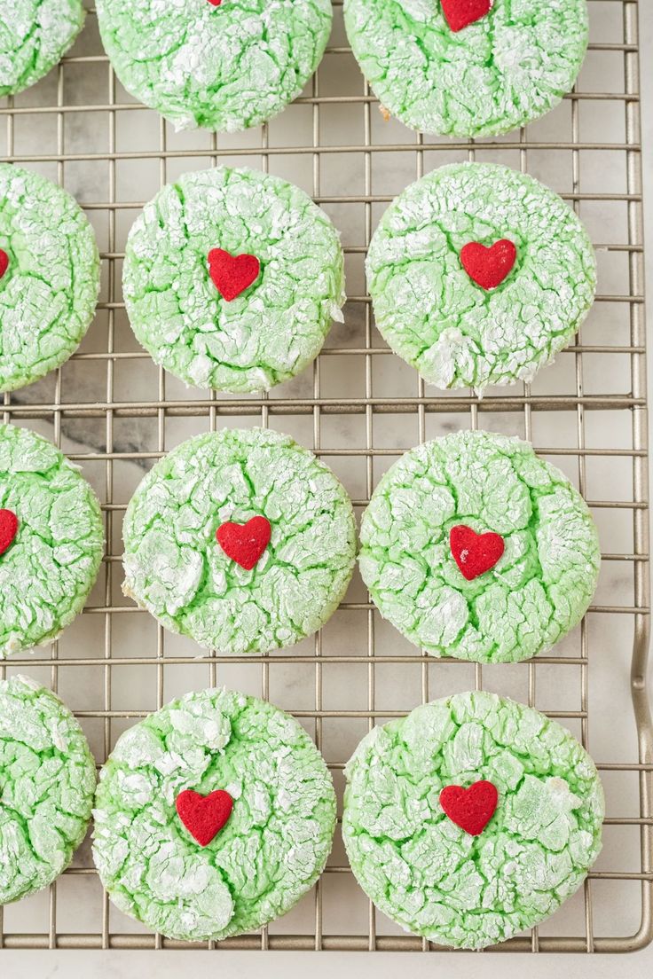 green cookies decorated with red hearts and frosting on a cooling rack, ready to be eaten