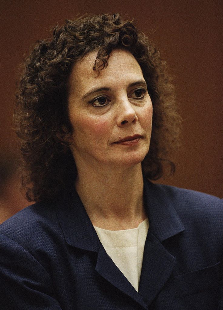 a woman with curly hair sitting in front of a microphone and looking off to the side