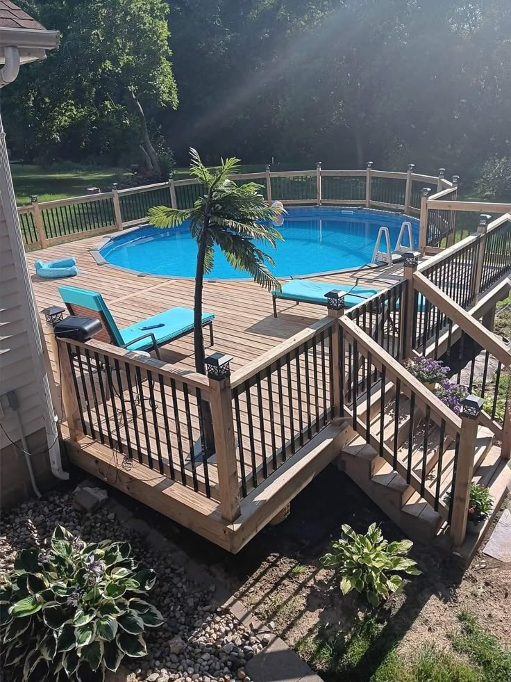 an above ground swimming pool with decking and palm tree in the foreground, surrounded by greenery