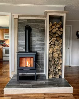 a wood burning stove sitting inside of a living room next to a pile of logs