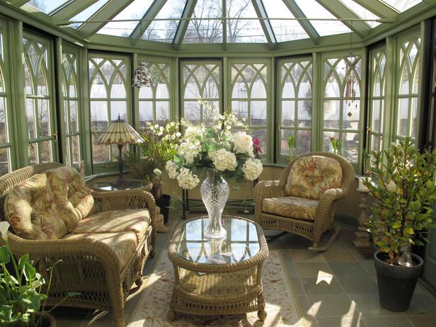 a sun room with wicker furniture and flowers in the vase on the coffee table