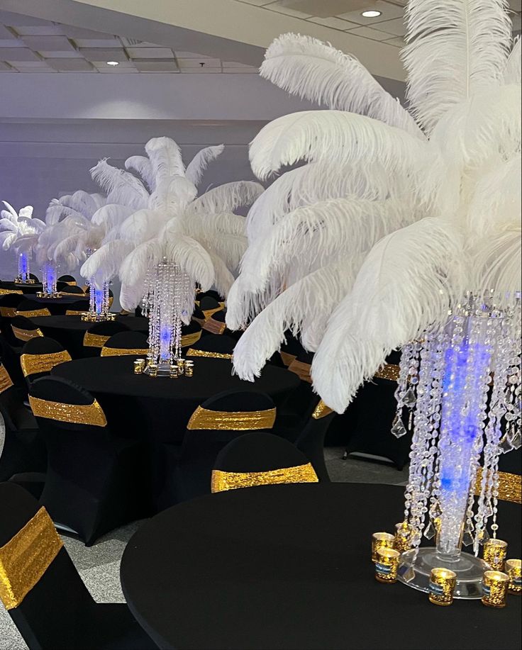 a room filled with black tables covered in white and gold decorations