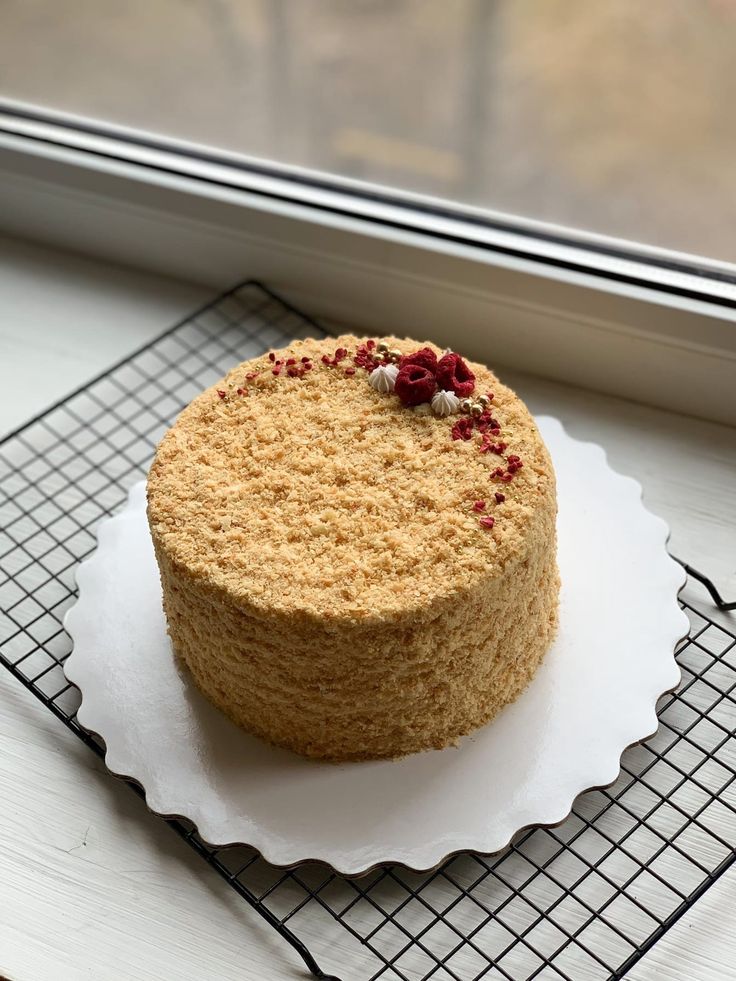 a round cake sitting on top of a white plate next to a window sill