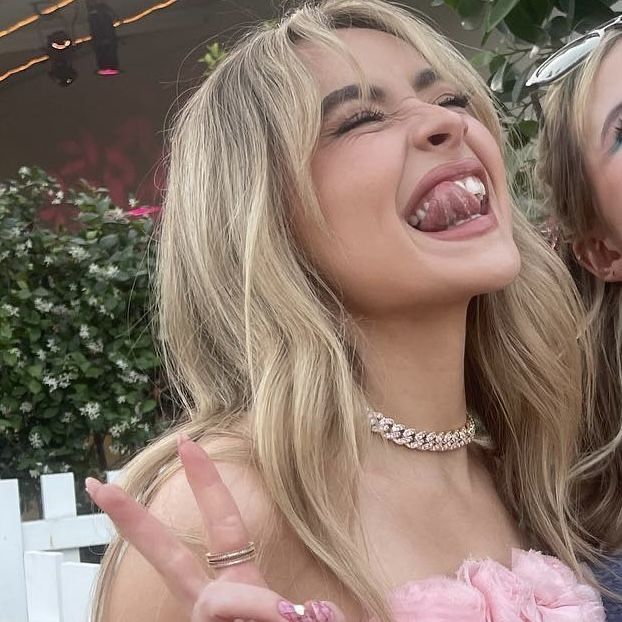 two beautiful young women standing next to each other with their hands in the air and smiling