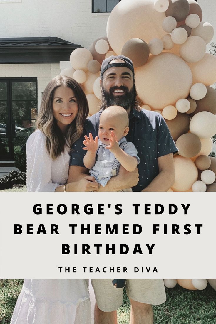 a man and woman holding a baby standing in front of a large balloon sculpture with the words george's teddy bear themed first birthday