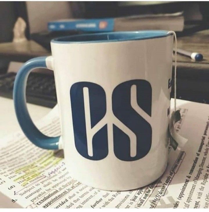 a blue and white coffee mug sitting on top of a table next to a keyboard