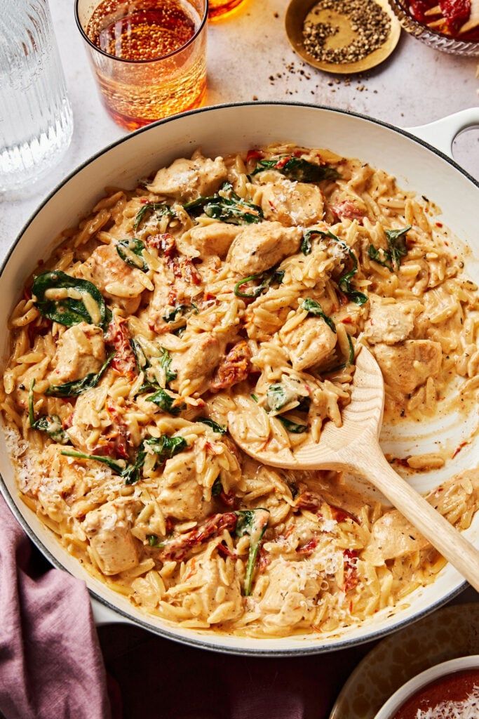 a pan filled with pasta and spinach on top of a table next to other dishes