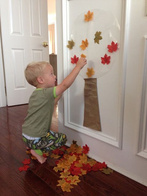 a little boy playing with leaves in front of a white door and the words toddler approved easy fall tree activity for toddlers