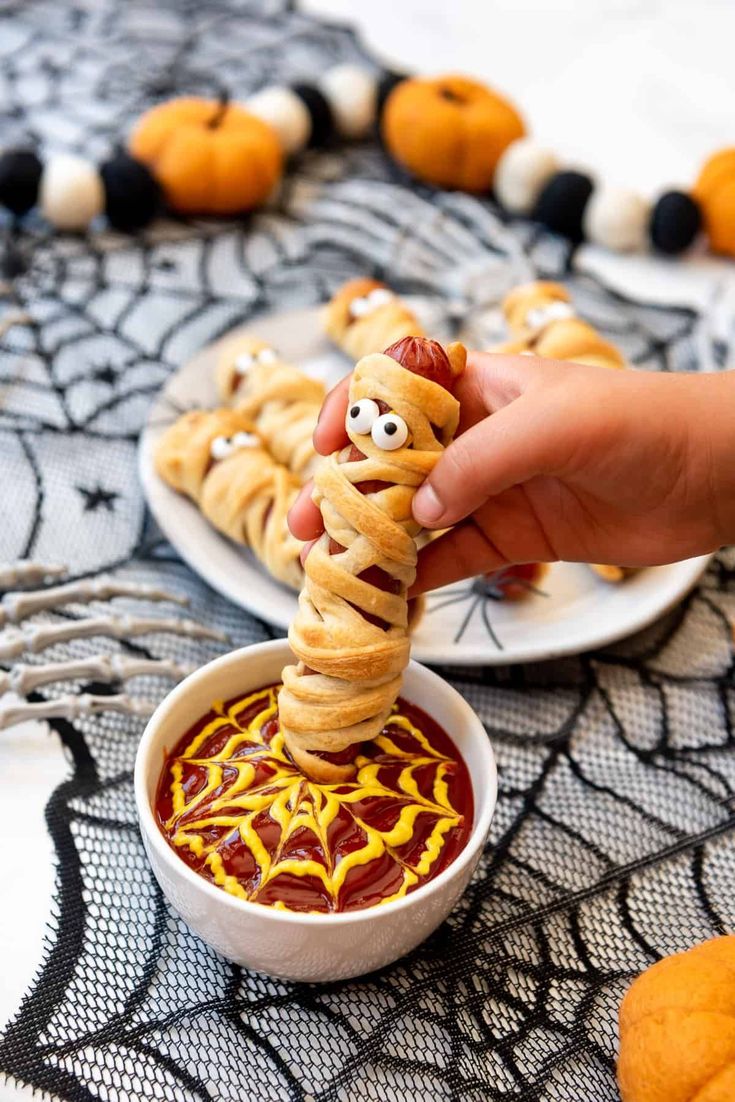 a person dipping some kind of food in a bowl with googly eyes on it