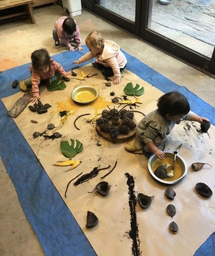 three children are sitting on the floor playing with food