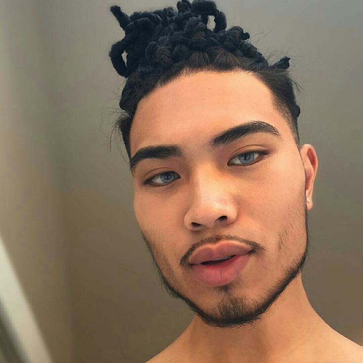 a man with braids on his hair looks at the camera