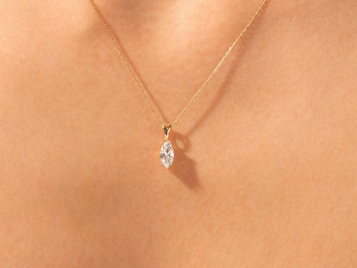 the back of a woman's neck wearing a gold necklace with a single diamond