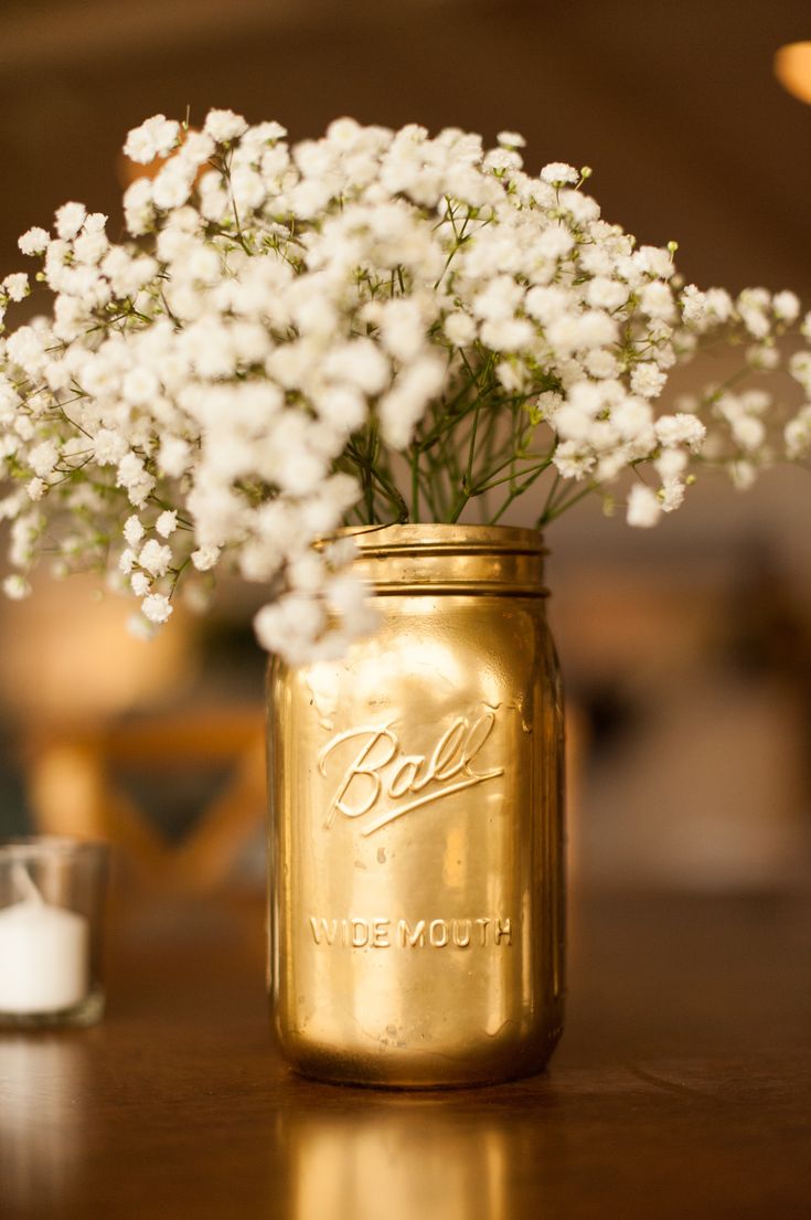 a mason jar filled with baby's breath sitting on top of a wooden table