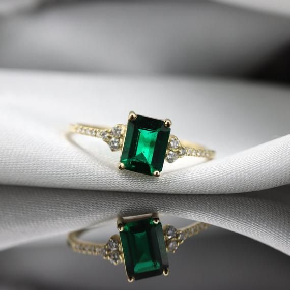 Handmade by an inspired jewelry artist team with decades of experience in the craft of jewelry making.Each gemstone, each diamond is carefully picked.Using only the finest raw materials and the highest industry standard in manufacturing, design and finish.A beautiful vintage inspired piece handmade just for you.An impressive radiant cut emerald brings rich color to this ring, contrasted by brilliant diamond side stones set in a shimmering 10,14 or 18 Karat gold setting.Ring Features:- Gemstone i Timeless Emerald Diamond Wedding Ring, Classic Emerald Promise Ring With Birthstone, Green Emerald Diamond Ring With Accents, Timeless Emerald Anniversary Ring, Timeless Emerald Wedding Anniversary Ring, Timeless Emerald Gemstone Wedding Ring, Classic Emerald Ring For Promise, Promise Emerald Ring In Yellow Gold, Green Timeless Diamond Wedding Ring