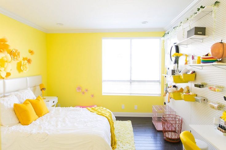 a bedroom with yellow walls, white bedding and lots of decorations on the wall