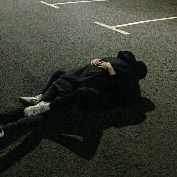 a man laying on the ground in front of a parking lot with his head down