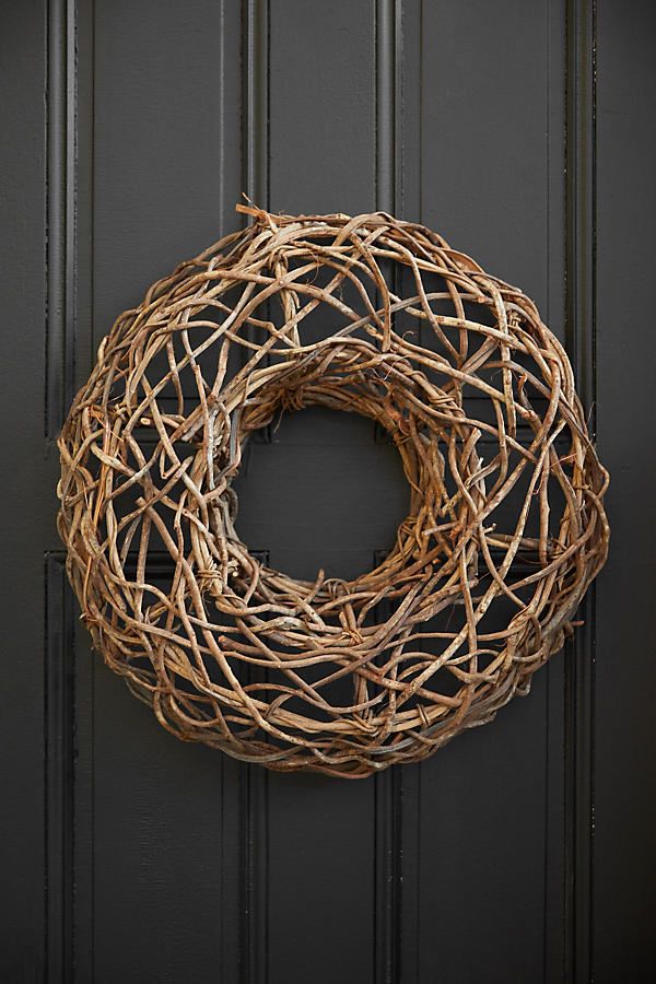 a close up of a wreath on a door with black paint and wood trimming