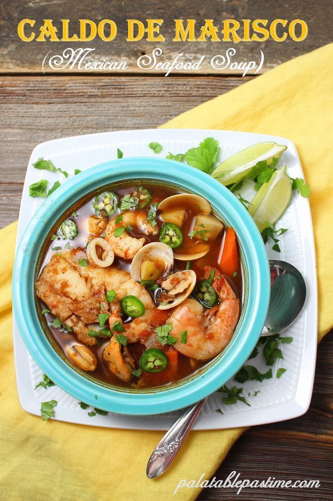 a blue bowl filled with seafood and veggies on top of a white plate