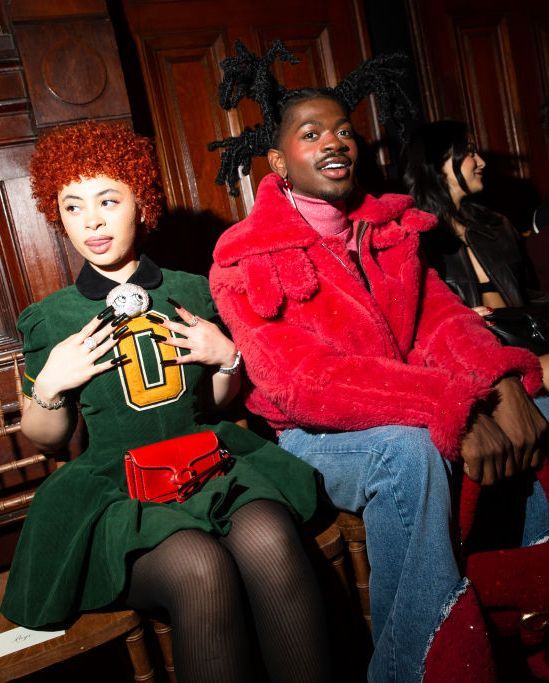 two people sitting next to each other in front of wooden paneled walls, one with red hair and the other wearing green