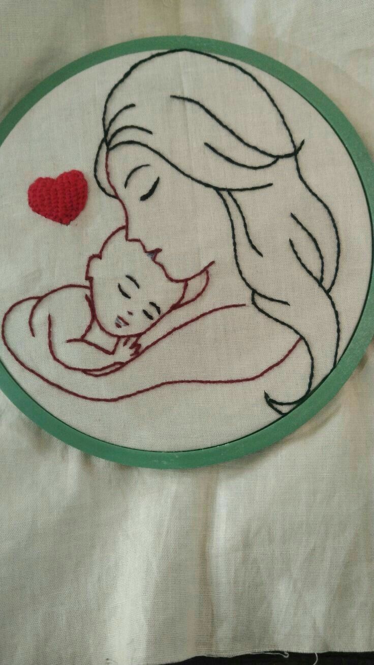 a hand embroidered picture of a woman holding a baby in her arms with a red heart on it