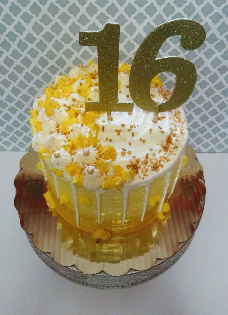 a cupcake with white frosting and yellow flowers on top that has the number sixteen on it