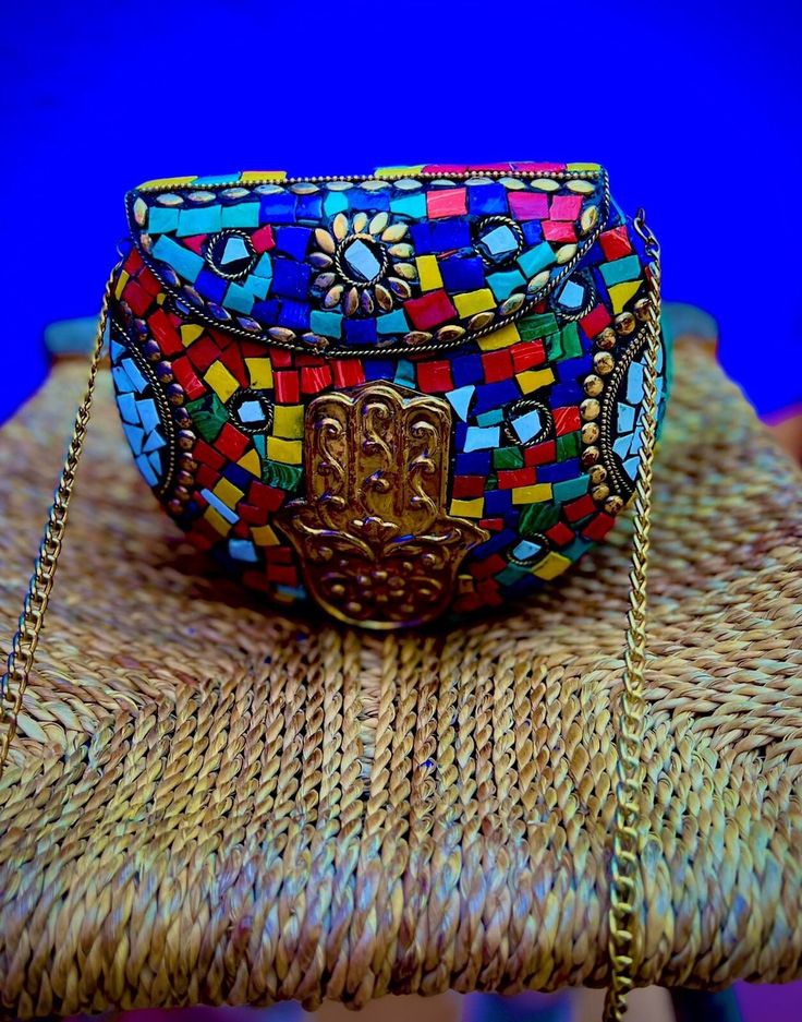 a colorful purse sitting on top of a wicker chair next to a blue wall