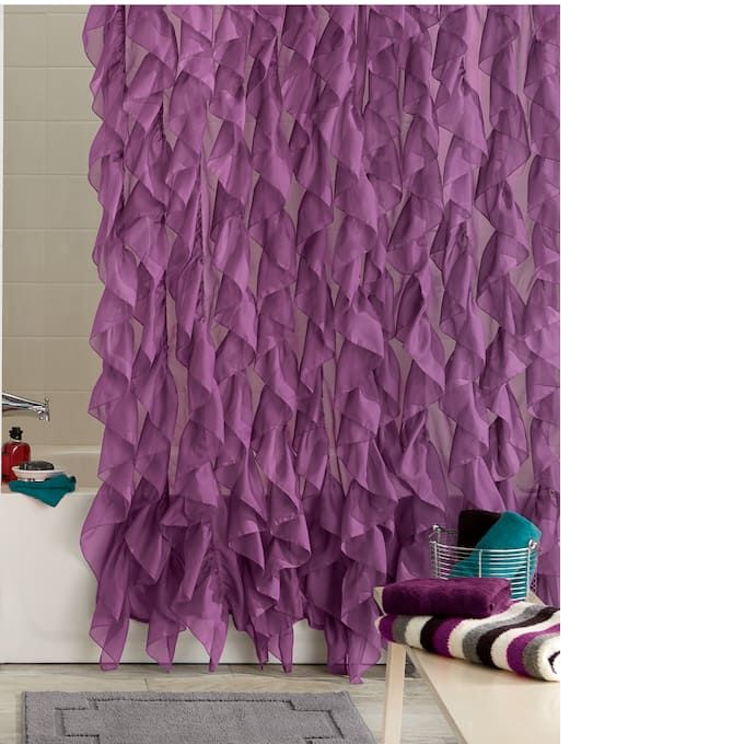 a purple shower curtain hanging on the side of a bathtub next to a rug