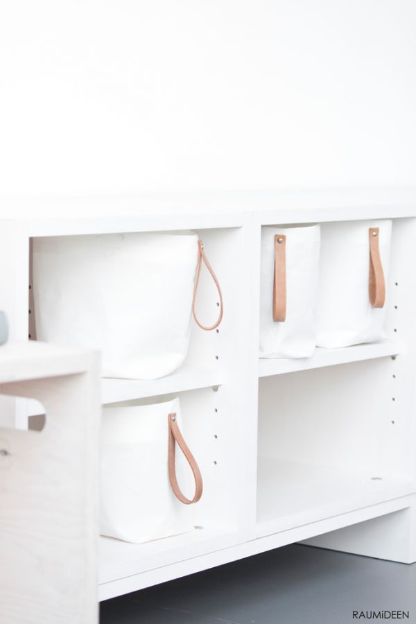 a white shelf with several purses hanging on it